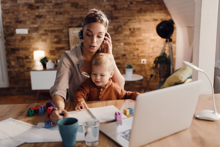 Imagem de Mãe trabalhando com filho pequeno no colo do post: 11 Dicas Eficientes para Mães Criarem uma Renda Digital 
